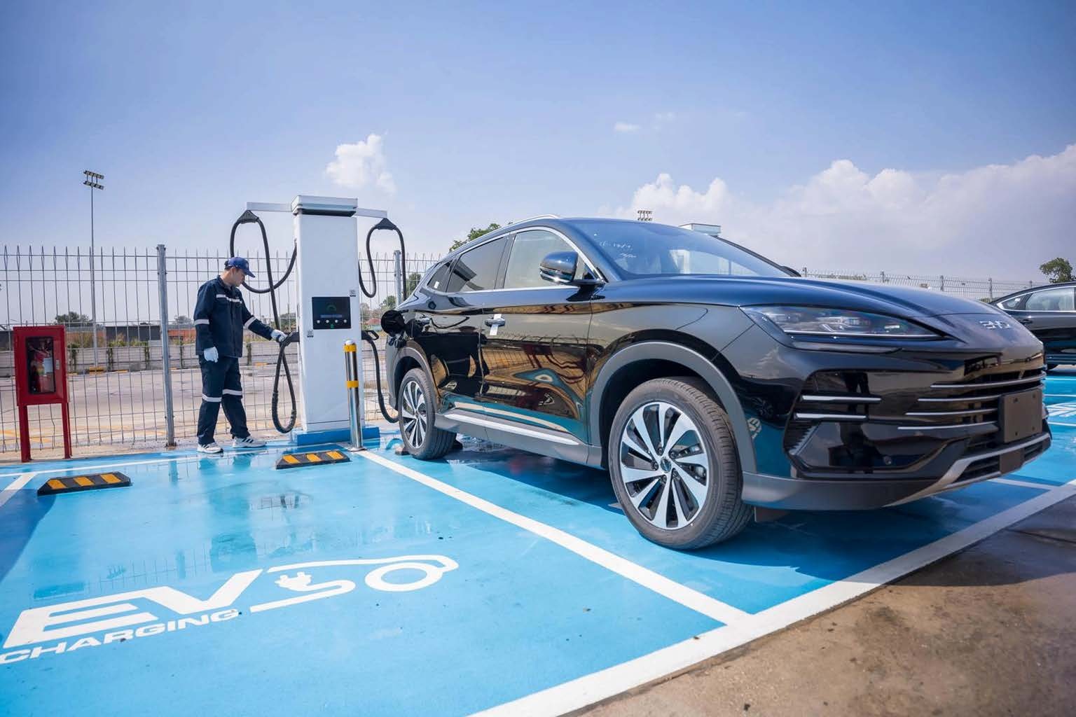 An electric vehicle connected to a DC charger with SIAM JWD operations staff